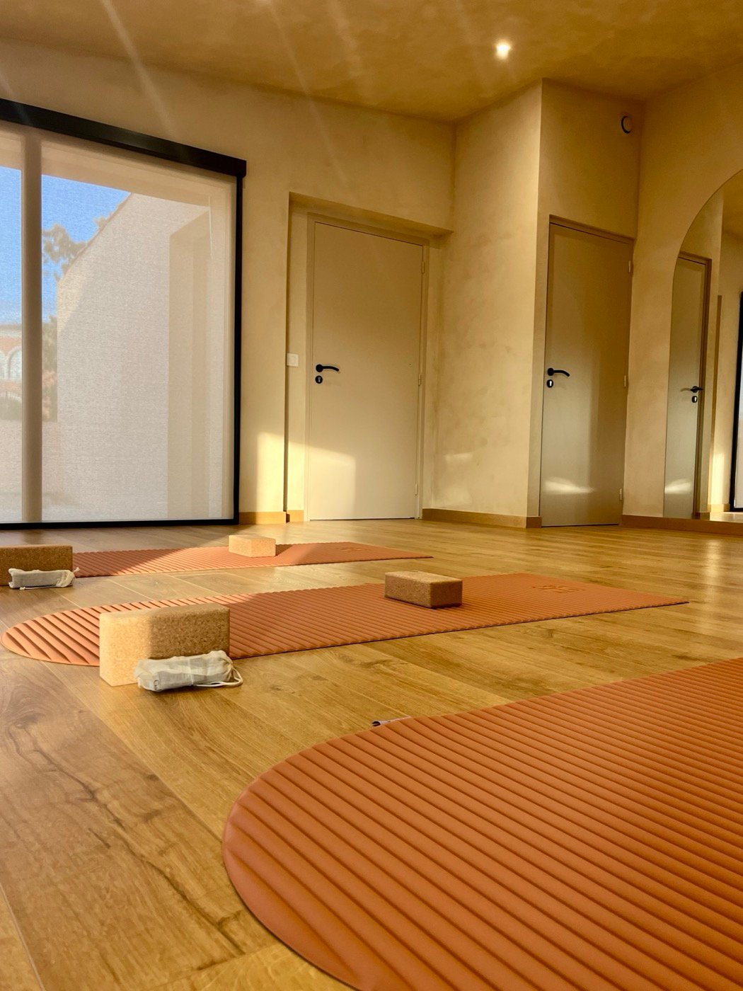 La salle vide, tapis terracotta et briques de liège dans la lumière du matin